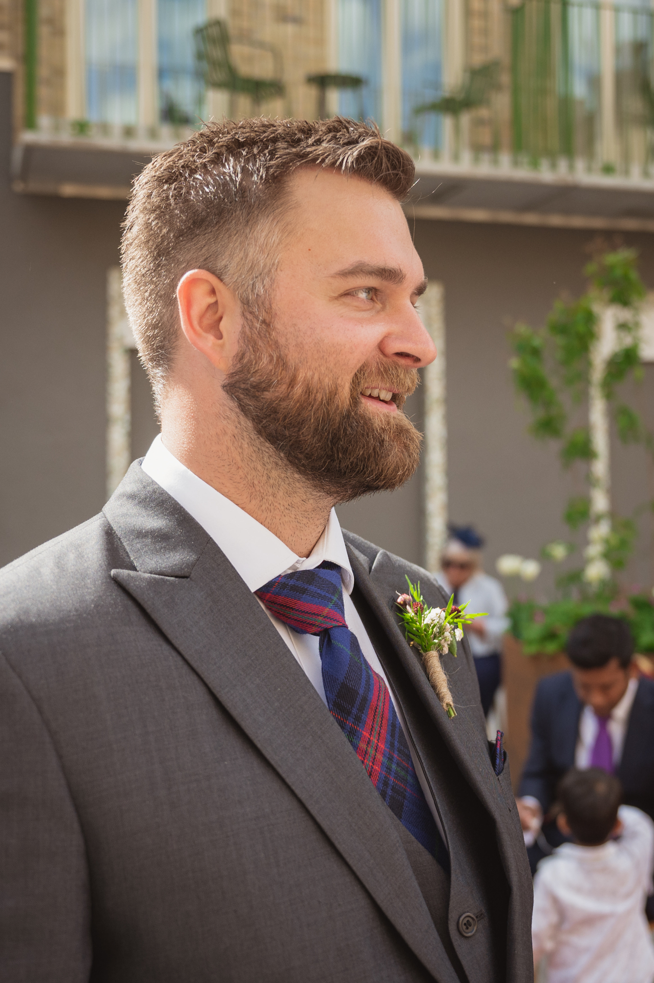 Martin in profile, suit and boutonnière, smiling